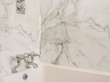 A bathtub with chrome taps in a bathroom at Upper Frogpool Cottage in Crediton