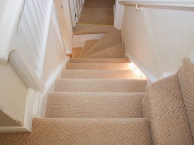 A staircase with carpet leading to a doorway at Upper Frogpool Cottage in Crediton