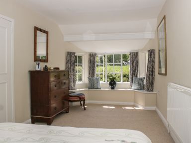 A bedroom with a dresser and window seat at Upper Frogpool Cottage in Crediton