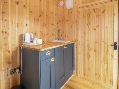 A kitchen with cabinets, a sink, kettle, and cups at Hazel