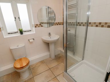 A bathroom with a shower, sink, toilet and mirror at Barley Cottage Oxwich