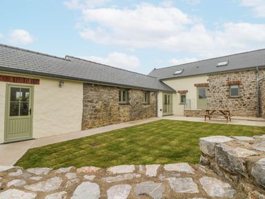 An outdoor area with stone walls and grass at Barley Cottage in Oxwich