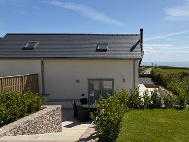 An exterior view of a modern house with grass and a pathway at Barley Cottage in Oxwich