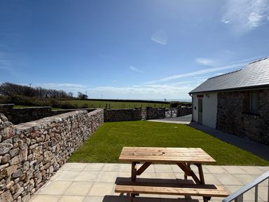 An outdoor area with a table and stone walls at Barley Cottage in Oxwich