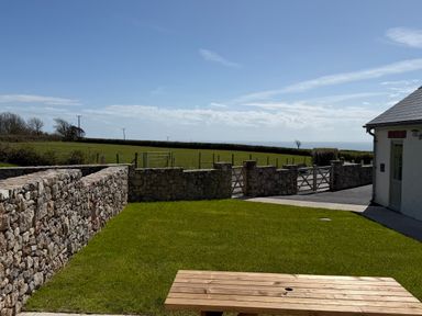 An outdoor area with a wooden table and stone wall at Barley Cottage in Oxwich