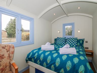 A bedroom with a bed in blue theme and a chair at Skye in Clee Hill