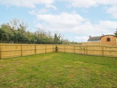 An outdoor garden with a grass area and wooden fence at Skye in Clee Hill