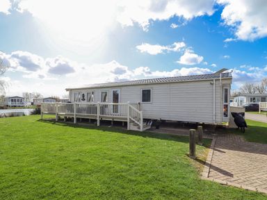 A mobile home with a deck and grassy area at 13 The Lakes Mablethorpe
