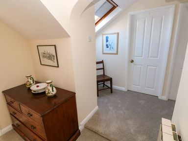 A hallway with a dresser and chair at Park Hall Cottage in Solva