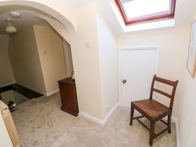 A hallway with a chair and skylight at Park Hall Cottage in Solva