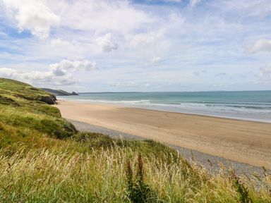 A beach with grass in the foreground at Park Hall Cottage in Solva