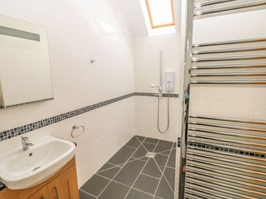 A bathroom with a sink, mirror, shower, and towel rack at Maerdy Lodge