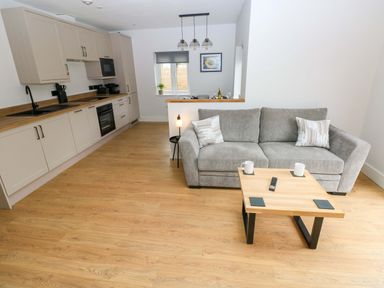 An open plan living area with a sofa and coffee table at Y Bwthyn in Burry Port