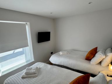 A bedroom with two beds and a television at Y Bwthyn in Pembrey