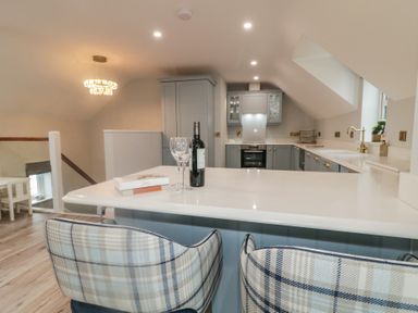 A kitchen with bar stools and a wine bottle at 2 Ard an Chuain Dunfanaghy