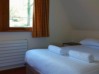 A bedroom with a bed and towels on it at Bracken Lodge in Finlakes Holiday Park near Chudleigh