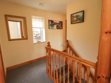 A hallway with a mirror, window, and pictures at 4 Mellbecks Mews Kirkby Stephen