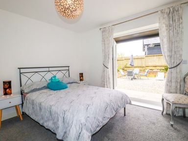 A bedroom with a bed and patio doors leading to an outdoor area at Meadow Retreat in Wadebridge