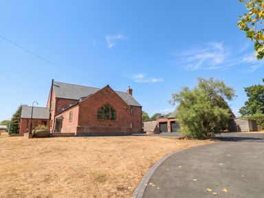 A house and garage with a driveway and tree at Hazeldene near Harvington