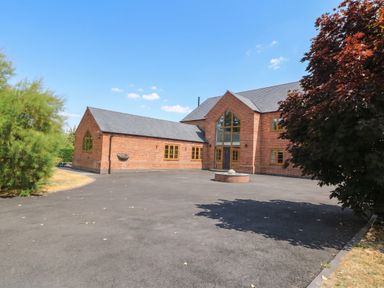 A house with a large driveway and surrounding trees at Hazeldene near Harvington