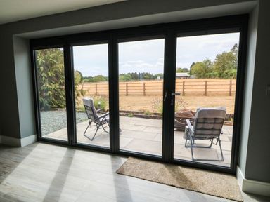 A view of a patio with chairs through sliding doors at Hazeldene near Harvington