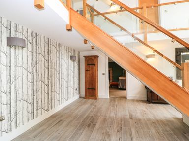 A hallway with a staircase and wooden cabinet at Hazeldene near Harvington