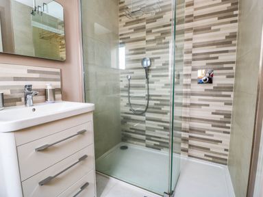 A bathroom with a shower, sink, and mirror at Hazeldene near Harvington