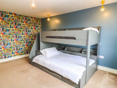 A bedroom with a bunk bed and colorful wallpaper at Hazeldene near Harvington