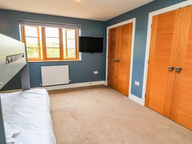 A bedroom with a bed, television, and window at Hazeldene near Harvington