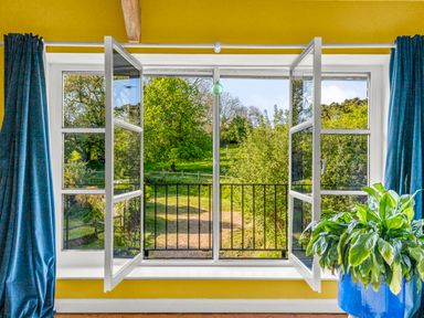 A living room with a window overlooking greenery at Chantry Studio in Kingsbridge