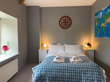 A bedroom with a bed and flowers on nightstands at Chantry Studio in Kingsbridge
