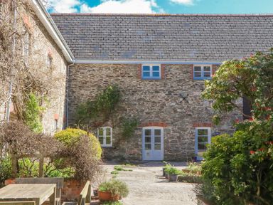 An outdoor area with stone building and garden features at Chantry Studio in Kingsbridge