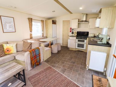 A kitchen area with a sofa and dining table at Sunflower Retreat, Caravan 61