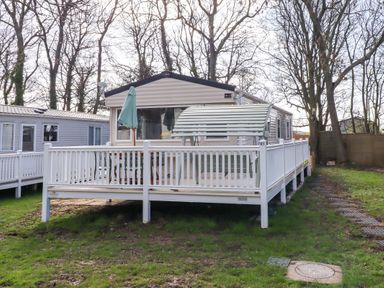 A caravan with a decking area and umbrella at Sunflower Retreat, Caravan 61
