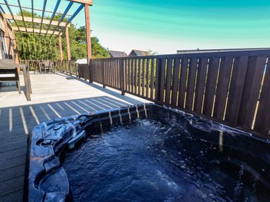 A patio with a hot tub and outdoor furniture at Warleggan in Portreath