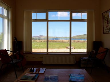 A living room with a guitar and a view of mountains and water at Welcome to the wild Atlantic way Mulroy Bay