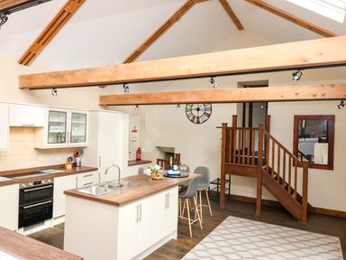 A kitchen with a staircase and bar stools at Cider Press Cottage in Torpoint