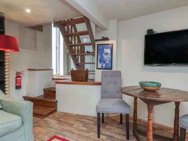 A living room with a staircase and television at The Bothy at Lewis Cottage Spreyton
