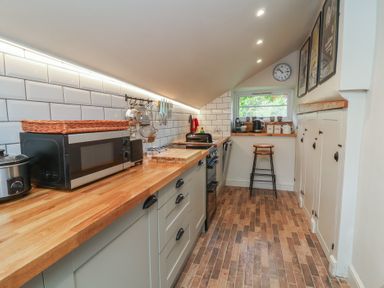 A kitchen with modern appliances and wooden countertops at The Bothy at Lewis Cottage Spreyton
