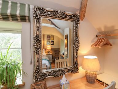 A bedroom with a mirror and a lamp at The Bothy at Lewis Cottage in Spreyton