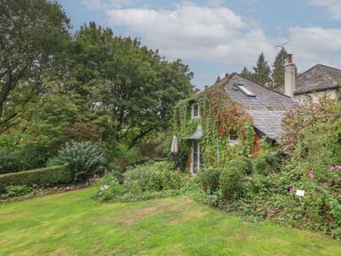 A house surrounded by garden and trees at The Bothy at Lewis Cottage in Spreyton