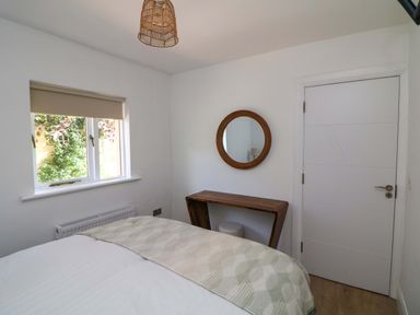 A bedroom with a bed, window, mirror, and table at The Mews @ Derrybawn Laragh, County Wicklow
