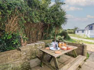 A garden with a picnic table and a plate of food at Swanny View in Swanage