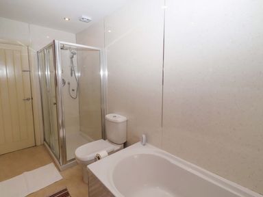 A bathroom with a shower and bathtub at Willow cottage Seahouses