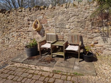 An outdoor seating area with wooden chairs and a table at Willow cottage Seahouses