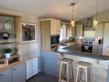 A kitchen with a sink, stools, and cabinetry at Yorkshire view lodge in Wilberfoss