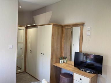 A bedroom with a wardrobe and a television at Yorkshire view lodge in Wilberfoss