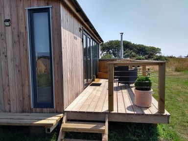 An outdoor deck with a hot tub and seating at Cleeves Cabins 2, Arran Luxury Lodge with hot tub, St. John's Town Of Dalry