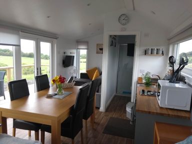 A living room with a dining table and sofa at Cleeves Cabins 2, Arran Luxury Lodge with hot tub in St. John's Town Of Dalry