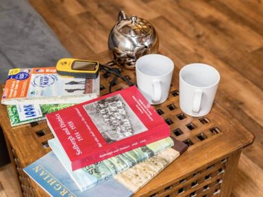 A living room with books and mugs on a wooden table at Sedbergh Penthouse - KingBed - Tv - Wifi Sedbergh